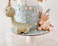 there is a cake decorated with animals on the top of it and balloons in the air