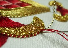 the thread is being sewn together with gold and red beads on top of it