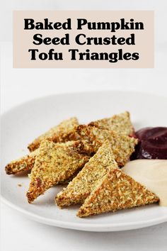 baked pumpkin seed crusted tofu triangles on a white plate with cranberry sauce