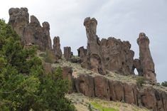 some very tall rocks and trees on a hill