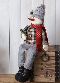 a stuffed snowman sitting on top of a wooden box