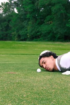 a man laying on the ground with a golf ball in his hand