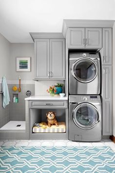 a washer and dryer in a small room with blue rug on the floor