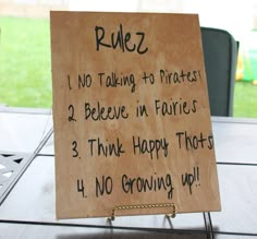 a wooden sign with writing on it sitting on top of a table next to a chair