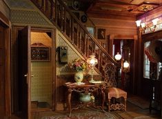 an ornate entry way with wooden stairs and floral arrangement on the table in front of it