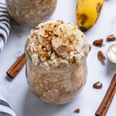 a glass jar filled with oatmeal next to two bananas and cinnamon sticks