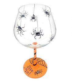 a wine glass decorated with bugs and spider webs on an orange base is shown in front of a white background