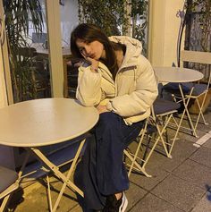 a woman sitting at a table talking on her cell phone