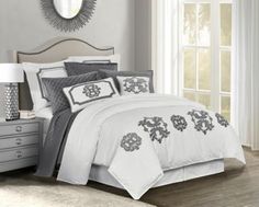 a bed with white and grey comforters in a room