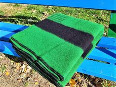 a green and black blanket sitting on top of a blue bench