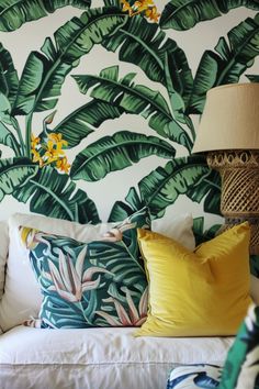 a white couch sitting next to a lamp on top of a wooden table in front of a green and yellow wall