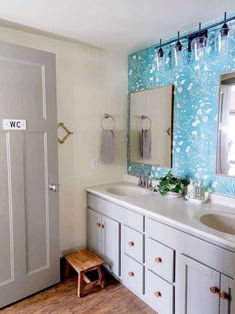 a bathroom with blue and white wallpaper, wooden flooring and double sink vanity