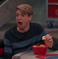 a man sitting at a table with a bowl of food in front of his face