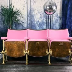 three pink chairs sitting next to each other in front of a mirror and disco ball