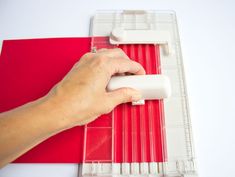 a person is using a ruler to cut red paper