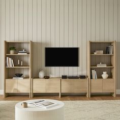 a living room with bookshelves and a flat screen tv mounted on the wall