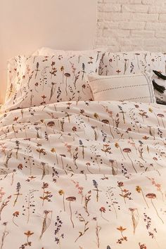 a cat is sitting on the edge of a bed with white sheets and floral print