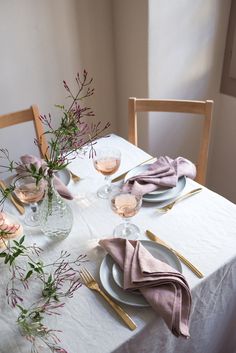 the table is set with plates, silverware and flowers in vases on it