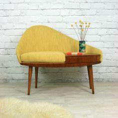 a yellow couch sitting on top of a wooden table next to a white brick wall