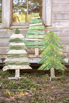 three wooden christmas trees sitting in front of a window on the side of a building