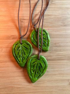 three green leaf shaped pendants on a wooden surface