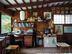 a home office with lots of books and pictures on the wall, along with a desk