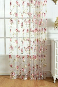 a white curtain with pink flowers on it in front of a window and a dresser