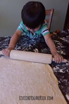 a young boy rolling dough on top of a table