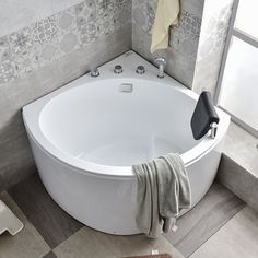 a bathroom with a large white bathtub next to a window