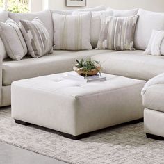 a living room filled with lots of white couches and pillows on top of a rug