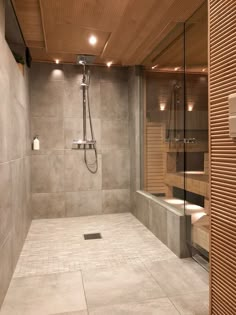 a bathroom with a walk in shower sitting next to a toilet and sink under a wooden ceiling