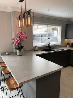 a kitchen with an island and bar stools next to the counter top in front of a window