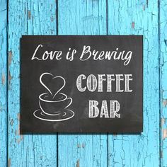 a chalkboard sign that says love is brewing coffee bar on a blue wooden background