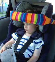 a young child sleeping in a car seat with a stuffed animal on it's head