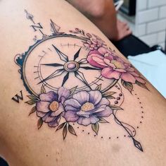 a woman's back with flowers and a compass tattoo