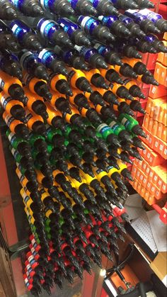 many bottles are stacked on top of each other in a store display case with orange, green, and blue caps