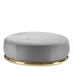 a round ottoman with gold legs and a grey velvet cover on top, sitting in front of a white background