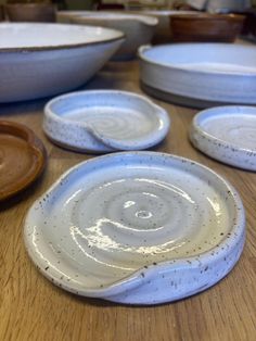 several white dishes sitting on top of a wooden table