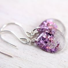 a pair of earrings with purple and silver glitter