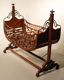 a wooden cradle with an iron frame on wheels