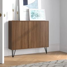 a wooden cabinet sitting on top of a hard wood floor next to a white wall