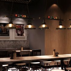 a restaurant with several tables and stools in front of the bar area, along with hanging lights