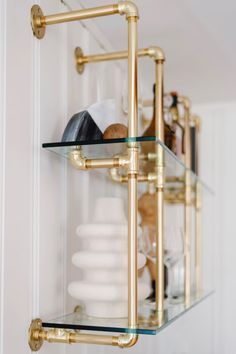 two glass shelves with gold fixtures and white dishes in the background, all stacked on top of each other