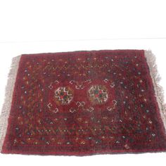 a red rug with two medallions on the middle and one in the middle, sitting on a white surface