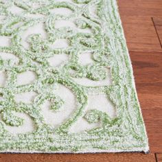 a green and white area rug on the floor with wood flooring in the background