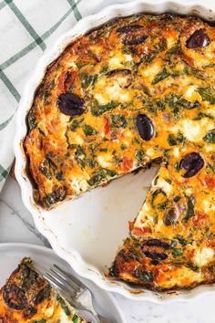 a quiche with olives and spinach in a pie pan on a table