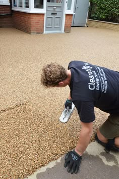 a man in black shirt working on a driveway