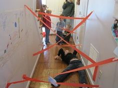 a man laying on the floor in front of a wall with red tape taped to it