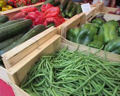 several wooden boxes filled with green beans and cucumbers, all in different shapes and sizes