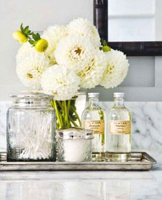 white flowers are sitting on a tray in front of a mirror and some bottles with spices